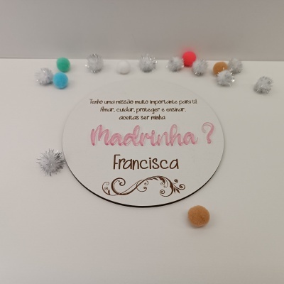 Placa redonda branca com texto decorativo e pompons coloridos e prateados ao redor