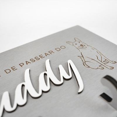 Placa cinzenta com desenho de cão e texto em relevo branco.