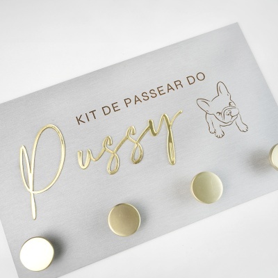 Cartão cinza com texto em relevo dourado Pussy e texto castanho KIT DE PASSEAR DO com desenho de cão.