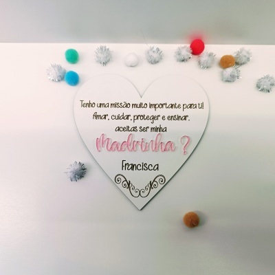 Placa de madeira coração com texto e bolas de pompom coloridas ao redor