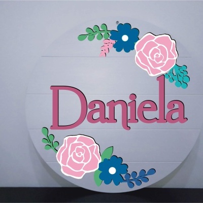 Placa redonda branca com flores decorativas e nome Daniela em letras cor de rosa