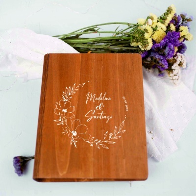Convite de casamento em madeira com gravação branca floral e texto acompanhado de flores secas e tecido branco