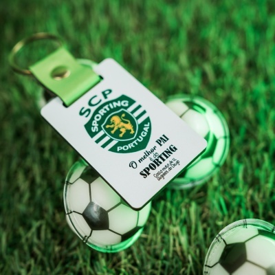 Porta-chaves com logotipo do Sporting Clube de Portugal e texto dedicado a pai, sobre relva.