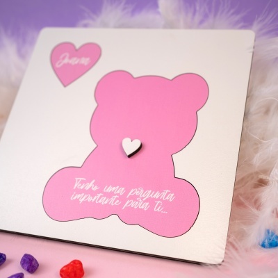 Cartão com urso e texto em português com fundo de penas brancas e pedras coloridas
