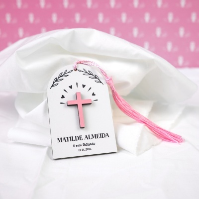 Etiqueta de batizado branca com cruz rosa e tassel rosa sobre tecido branco
