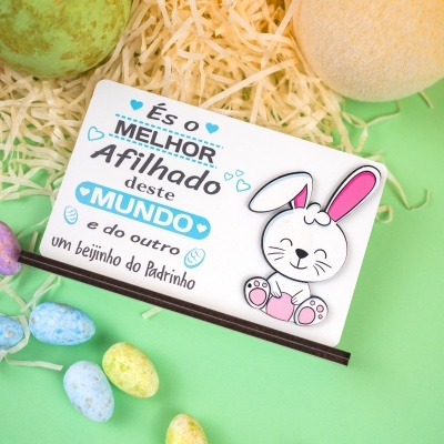 Cartão decorativo com texto em português e desenho de coelho rodeado por tiras de papel e ovos coloridos