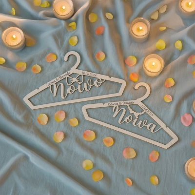 Cabides de madeira personalizados de casamento com velas e pétalas sobre tecido azul.
