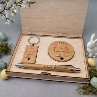 Conjunto de presente em madeira com texto para padrinho dentro de caixa aberta com decoração de ovos coloridos e coelho branco