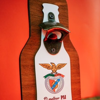 Abridor de garrafas de parede em madeira com placa branca e emblema colorido em fundo laranja