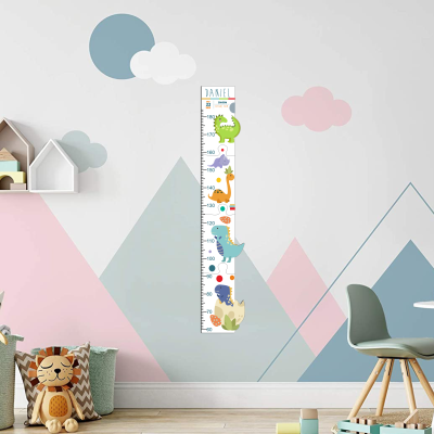 Medidor de altura infantil com dinossauros coloridos e nome Daniel numa parede com padrões geométricos pastel e nuvens