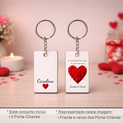 Dois porta-chaves com base branca e corações vermelhos, texto em português, em ambiente decorado com vela e flores.