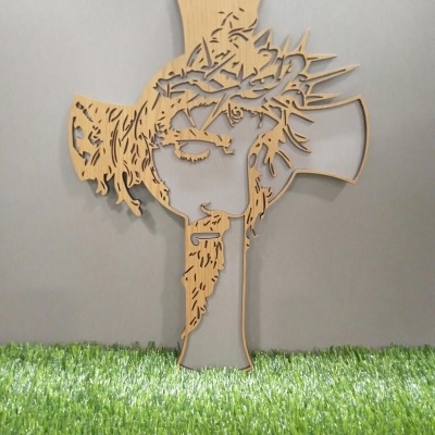 Escultura decorativa em madeira clara com rosto e coroa de espinhos sobre relva artificial