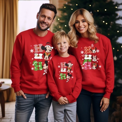 Família com sweatshirts vermelhas de Natal Disney Mickey e Minnie com árvore de Natal ao fundo