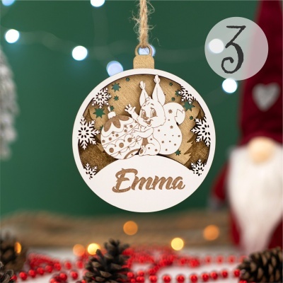 Enfeite de Natal em madeira clara com desenho de coelho e ovo decorado e a palavra Emma