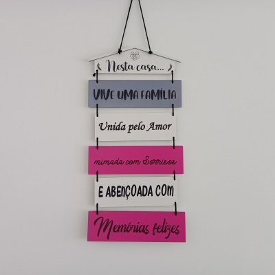 Placa decorativa em madeira pendurada com texto em português sobre família e amor.