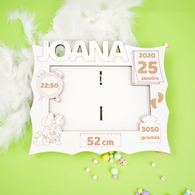 Moldura branca personalizada com nome JOANA e detalhes de nascimento num fundo verde com penas brancas