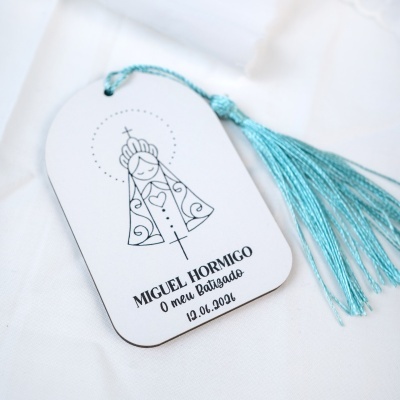 Etiqueta branca com ilustração religiosa e franja azul sobre tecido branco