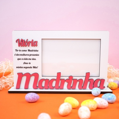 Moldura branca para fotografia com texto em vermelho e preto, decorada com doces coloridos sobre fundo laranja e rosa.
