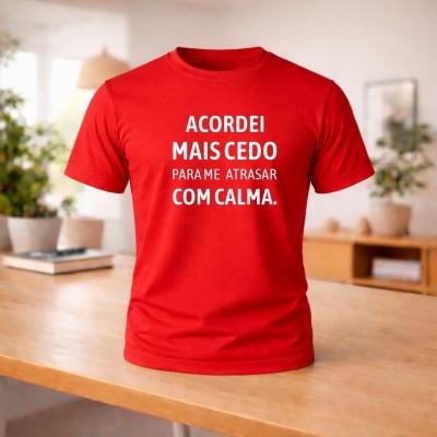 T-shirt vermelha com texto em branco sobre mesa de madeira num ambiente interior