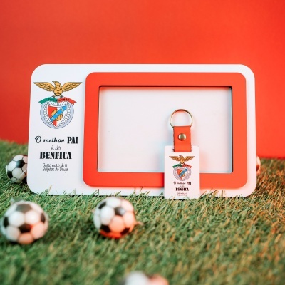 Suporte para fotografia ou porta-chaves em pele laranja com texto e emblema Benfica em fundo de relva com bolas de futebol pequenas.