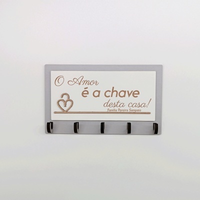 Suporte de parede com ganchos e placa decorativa com texto em português.