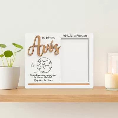 Moldura de fotografia branca com texto e decoração, numa prateleira com vaso e vela acesa