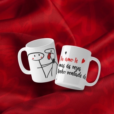 Duas canecas brancas com desenhos e texto em português sobre tecido vermelho.