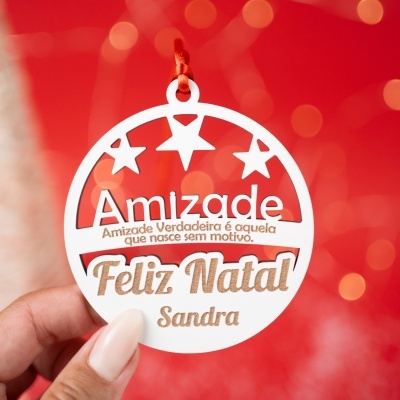 Etiqueta de Natal branca com estrelas recortadas e texto em castanho claro e escuro, pendurada por cordão vermelho