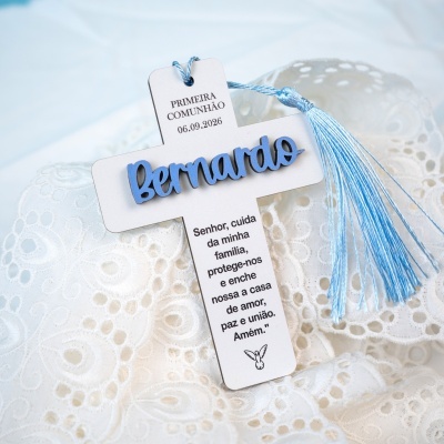 Cruz decorativa com nome Bernardo e cordão azul sobre tecido branco bordado