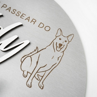 Placa metálica cinzenta com desenho de cão e texto gravado e em relevo