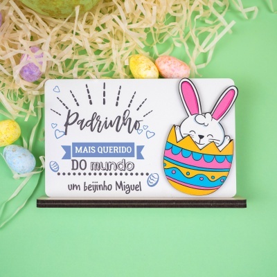 Placa decorativa de páscoa com coelho e texto para padrinho rodeada de ovos de páscoa e palha