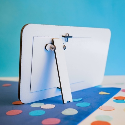 Suporte ou moldura branca com bordas castanhas sobre superfície azul com círculos coloridos.