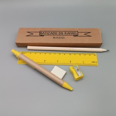 Estojo de papel castanho com texto preto, vários materiais de escrita e medição amarelos e brancos sobre fundo cinzento.