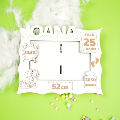 Moldura branca personalizada com nome e detalhes em glitter numa superfície verde.
