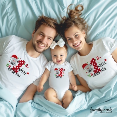 Família sorridente com roupa branca estampada de Natal a deitar em cama azul clara.