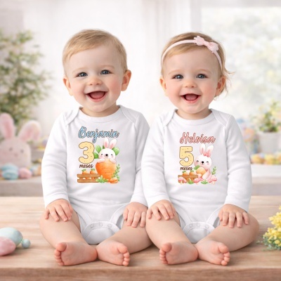 Dois bebés sorridentes com bodies brancos personalizados sentados num banco de madeira em ambiente interior claro.