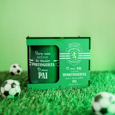 Caixa e copo verdes com texto branco e brasão do Sporting CP, sobre relva artificial com bolas de futebol