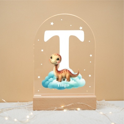 Objeto decorativo com a letra T, dinossauro e nome Tiago em base de madeira clara