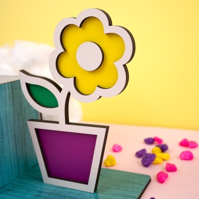 Objeto decorativo em madeira em forma de flor amarela com vaso roxo