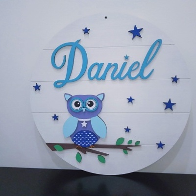 Placa decorativa redonda com nome Daniel, estrelas e coruja azul em madeira branca