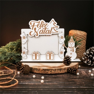 Moldura branca decorada com motivos natalícios e texto Feliz Natal em papel e cortiça