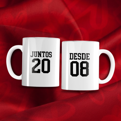 Duas canecas brancas com texto preto sobre tecido vermelho