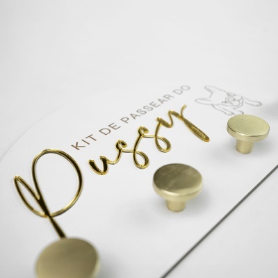 Cartão branco com botões de metal dourados e texto em dourado e castanho