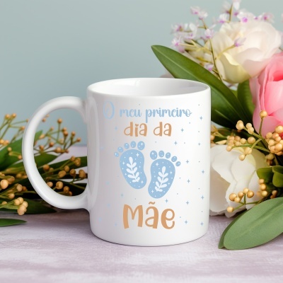 Caneca branca com texto O meu primeiro dia da Mãe e pegadas azuis rodeada de flores