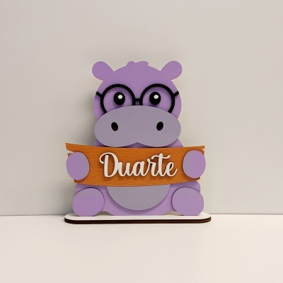 Boneco decorativo hipopótamo cor-de-rosa com óculos e placa de madeira com o nome Duarte