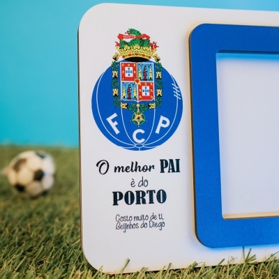 Moldura de madeira branca e azul com brasão FC Porto e texto para o melhor pai sobre relva com bola desfocada ao fundo