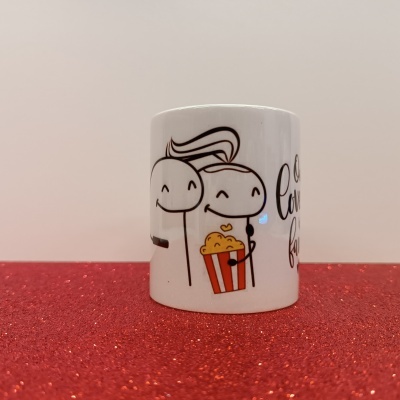 Caneca branca com ilustração a preto de personagens sorridentes e balde de pipocas