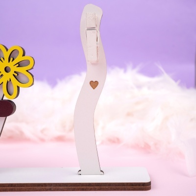 suporte branco de madeira com clip e coração gravado em fundo lilás e rosa felpudo