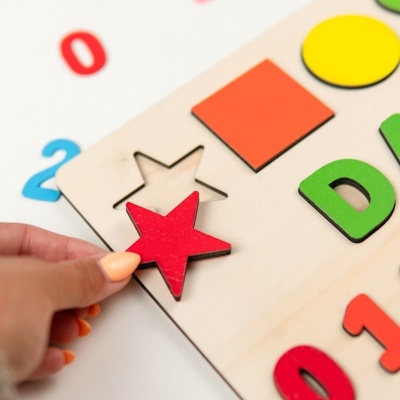 Jogo educativo de encaixe em madeira com peças coloridas e números.
