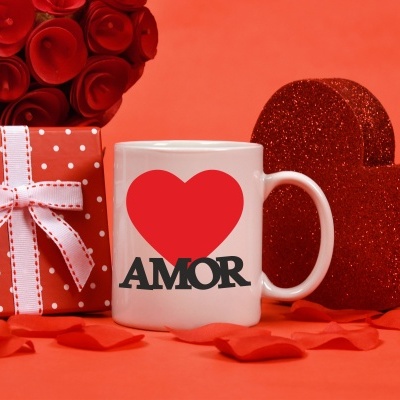 Caneca branca com coração vermelho e palavra AMOR, caixa de presente vermelha com bolinhas e laço, corações vermelhos brilhantes.